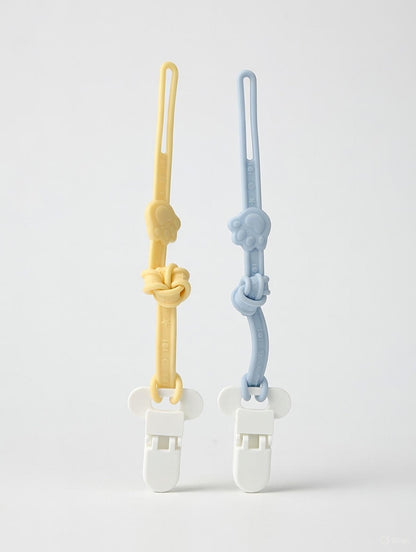 Two highly flexible teething pacifier clips in yellow and blue tied in gentle knots to showcase the ultra-soft food-grade silicone texture.